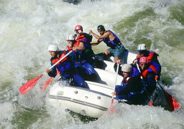 A group of people in life jackets are on a raft.